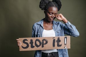 A woman tearfully holding a 'Stop it!' sign against racism in a powerful protest image.